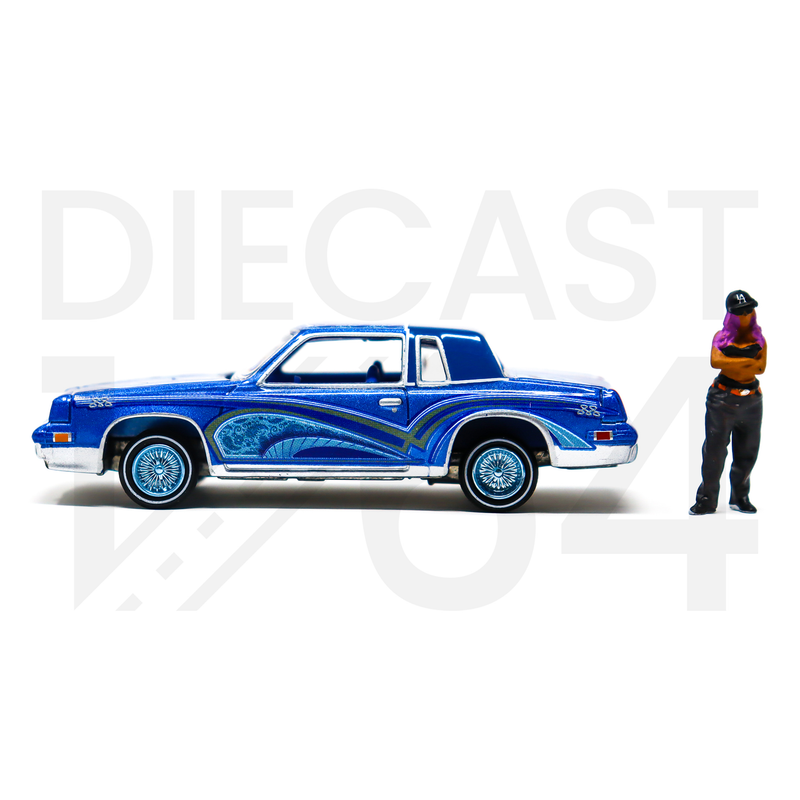Johnny Lightning 1:64 Lowriders 1984 Oldsmobile Cutlass with American Diorama Figure Limited 3,600 Pieces – Mijo Exclusives driver side with blue wheels